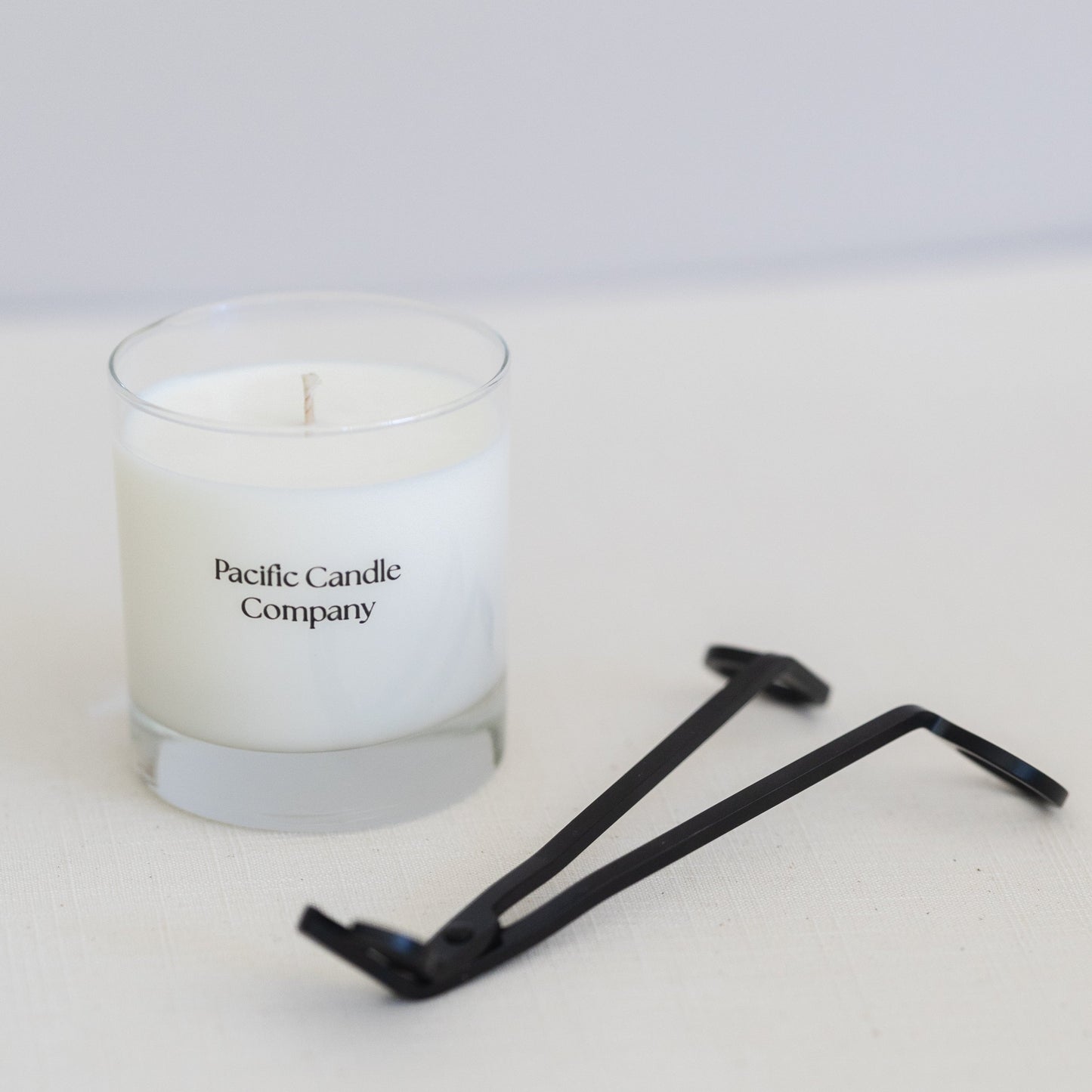 A single wick soy candle in a sleek glass jar, hand-poured with toxin-free wax and a cotton braided wick for a clean, even burn. Perfect for adding a warm glow and a subtle fragrance to any room. Scent: Coastal Cypress + Clementine.