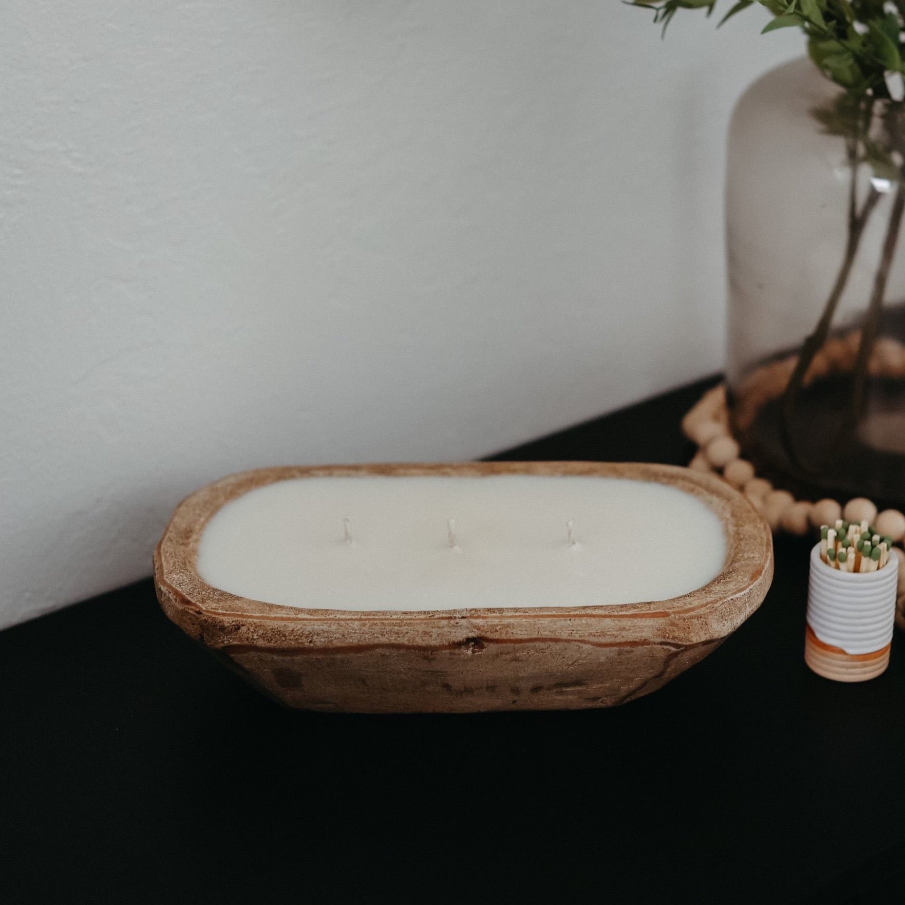 A rustic dough bowl candle made from hand-carved, sustainable wood, filled with creamy soy wax and multiple wicks for an inviting glow. A perfect statement piece for your home or a thoughtful gift. 
